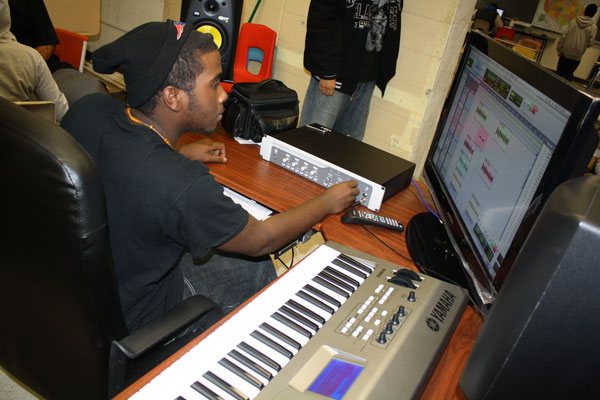 High School Sudent sitting at a computer and keyboard learning music production