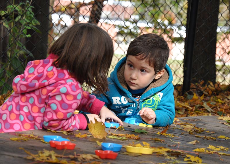 boy and girl in close conversation at outside table in the fall