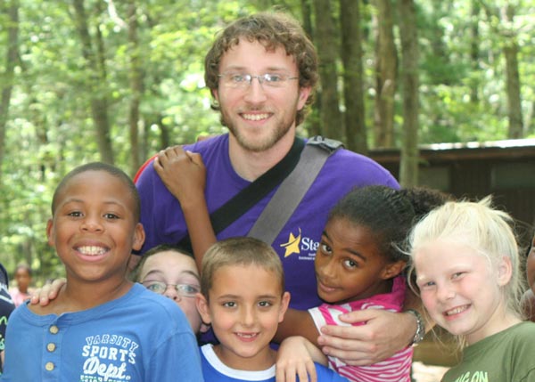 camp councelor hugging a diverse group of campers