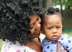 Caregiver hugging a skeptical infant