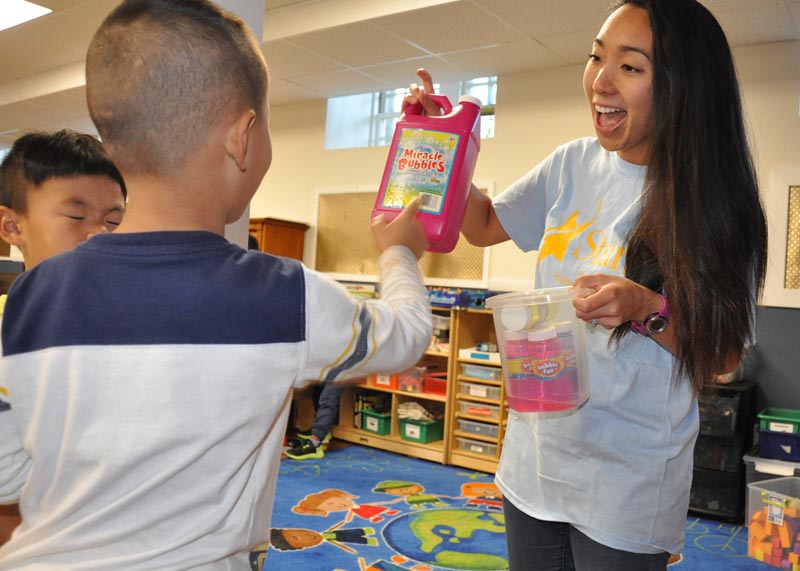 Teacher giving childrens bubbles to playwith at Atlantic afterschool program